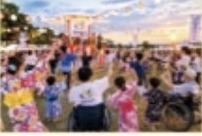 やぐらを囲んで浴衣の人や車いすの人が輪になって盆踊りをしている様子。
